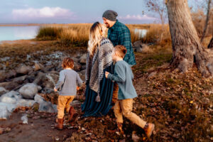 Family Photographer, a mom and dad walk outside as their young boys run beside them