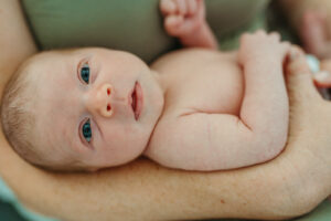 A woman holding a baby with blue eyes.