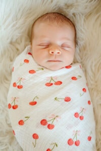A newborn baby is wrapped in a white swaddle.