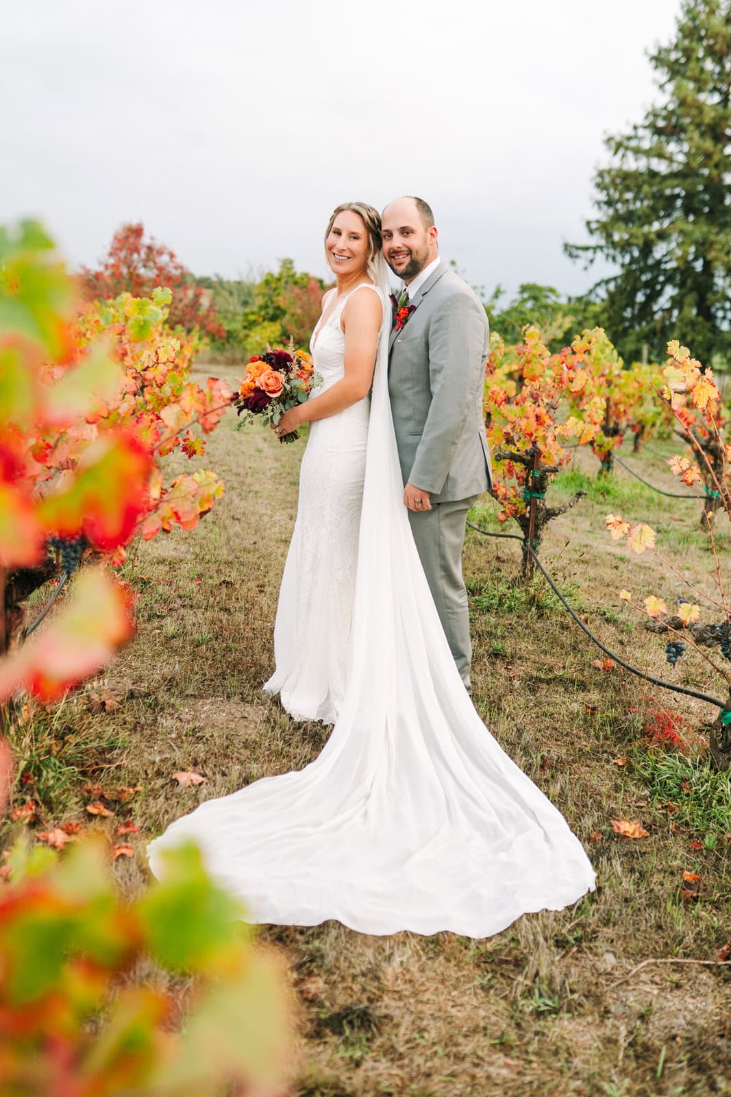 A bride and groom stand smiling in a vineyard in fall at one of the Sonoma wedding venues