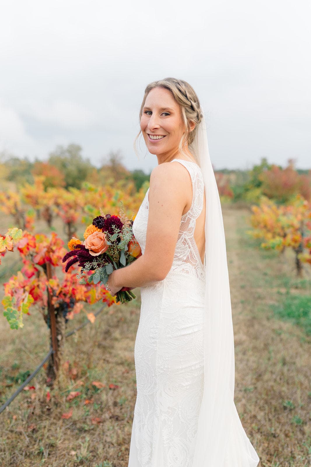 A bride smiles over her shoulder while exploring the vineyard at one of the Sonoma wedding venues