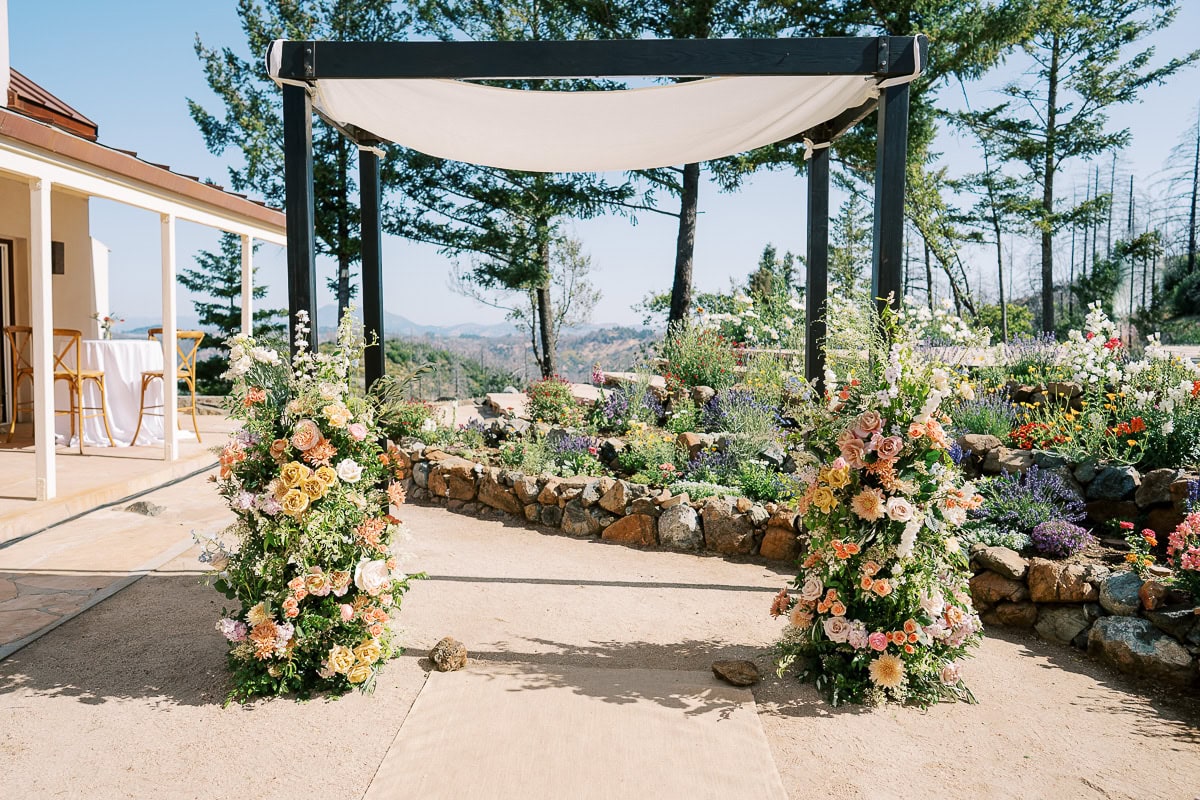 Ceremony arch decorated with flowers and greenery at Livermore vineyard wedding by Vanessa Montano Photography