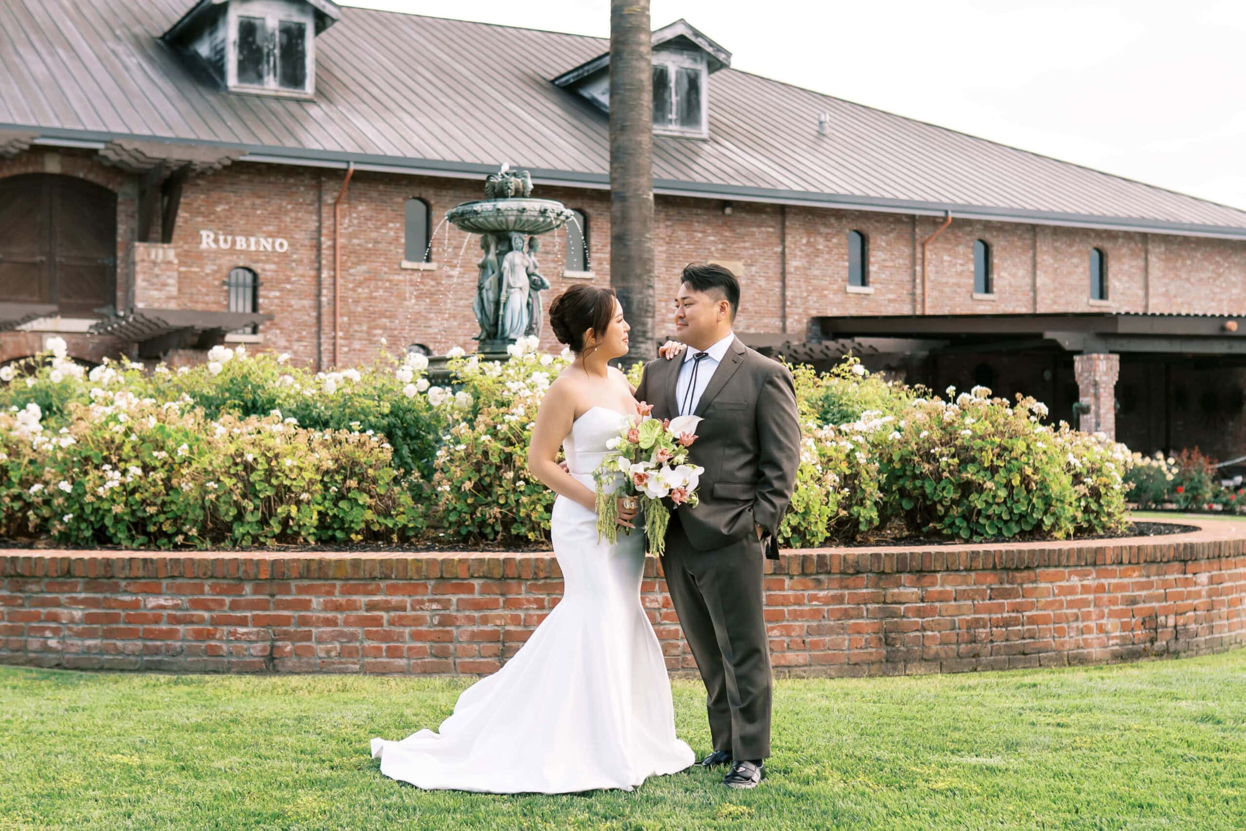 Bride and groom posing beside the fountain during their Palm Event Center wedding in Pleasanton, California