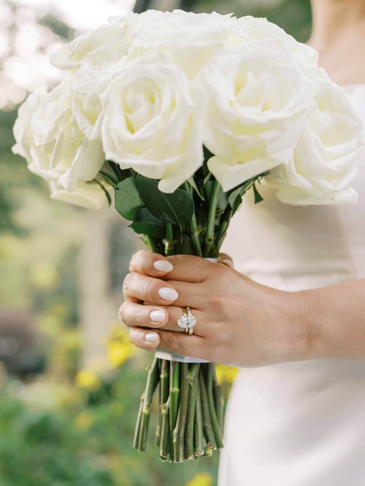 Bride holding a white rose bouquet beside the sunlit windows while getting ready for her Elliston Vineyards wedding.