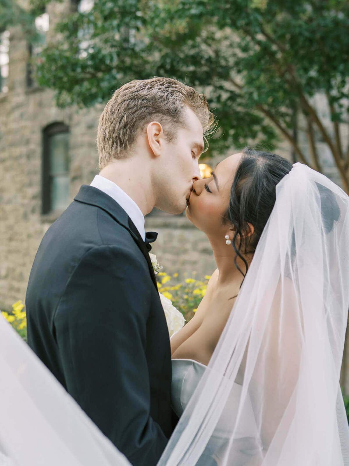 Bride and groom share a romantic kiss during their wedding portraits on the grounds of Elliston Vineyards in Sunol.