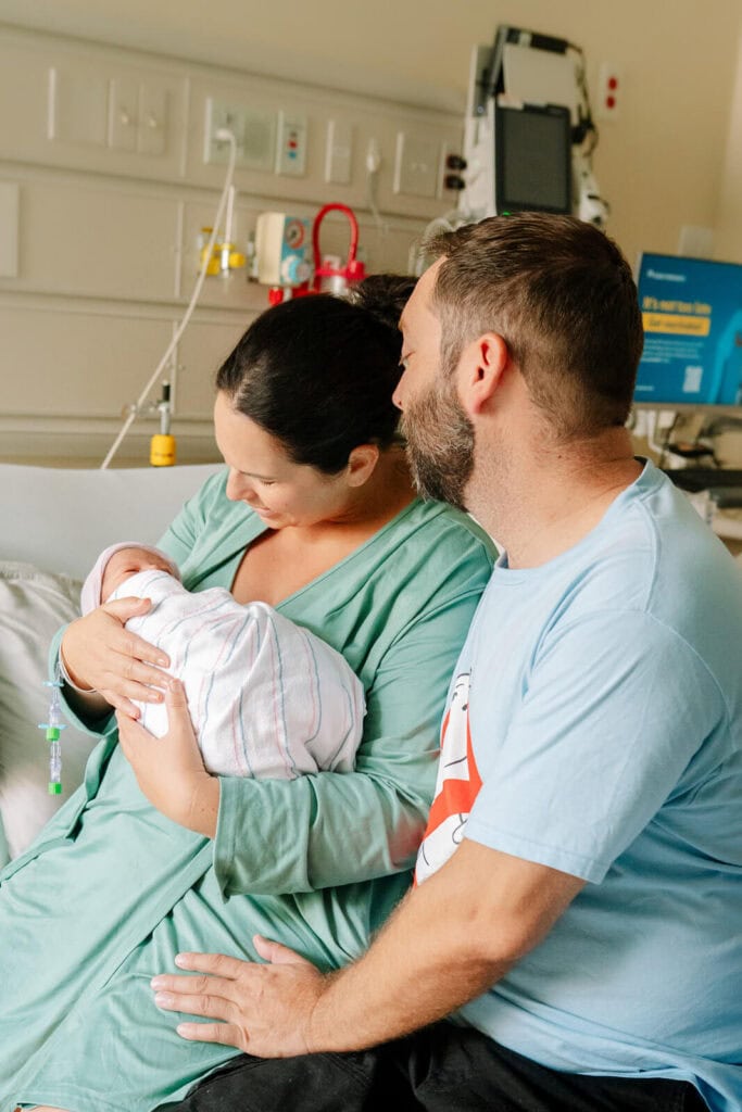 New parents cuddling their newborn during a natural Bay Area hospital newborn photography session